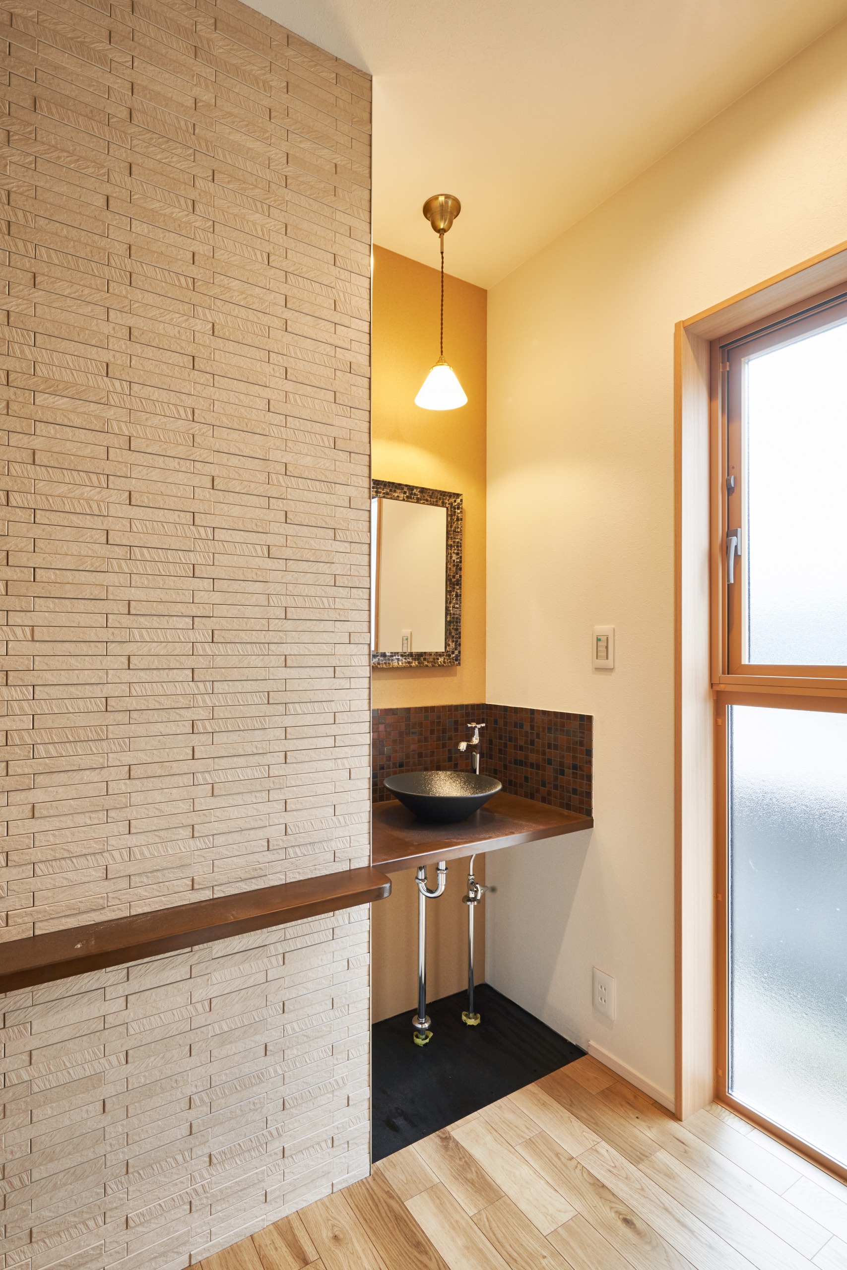 玄関横の造作洗面は、洗面台や鏡のタイル、照明がおしゃれな空間。