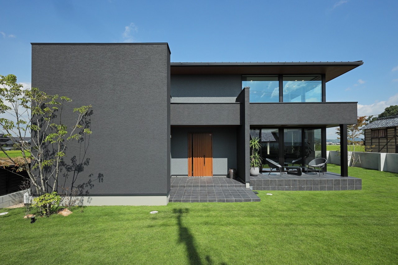家の顔でもある玄関は、やわらかなグレーと黒色の壁にナチュラルウッドのドアを採用。