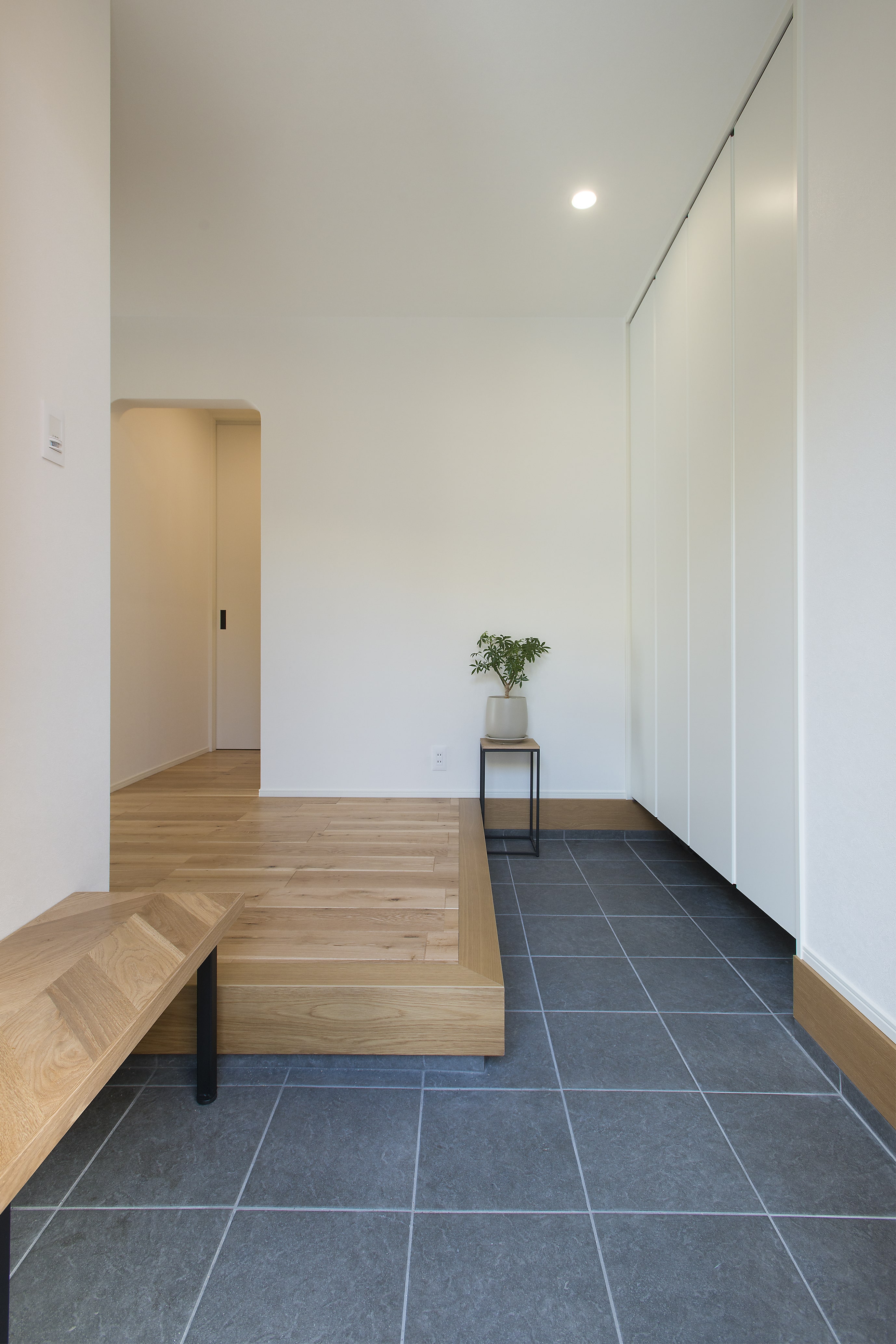 玄関の壁に沿って高く備えた収納スペースで、シンプルで美しい玄関を演出する。