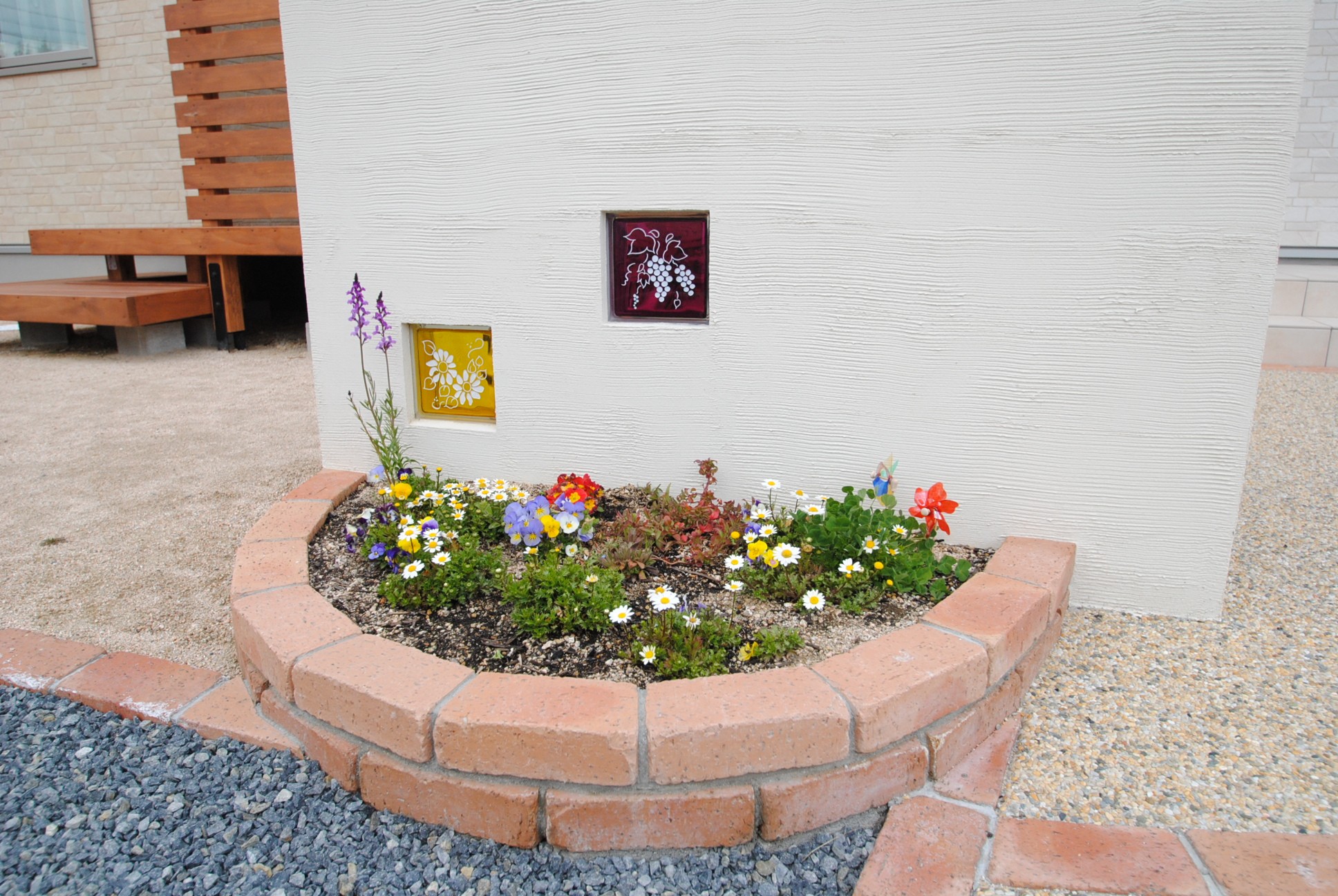 アプローチの門壁には花壇と調和するガラスブロックがあり、さり気なく色を添える