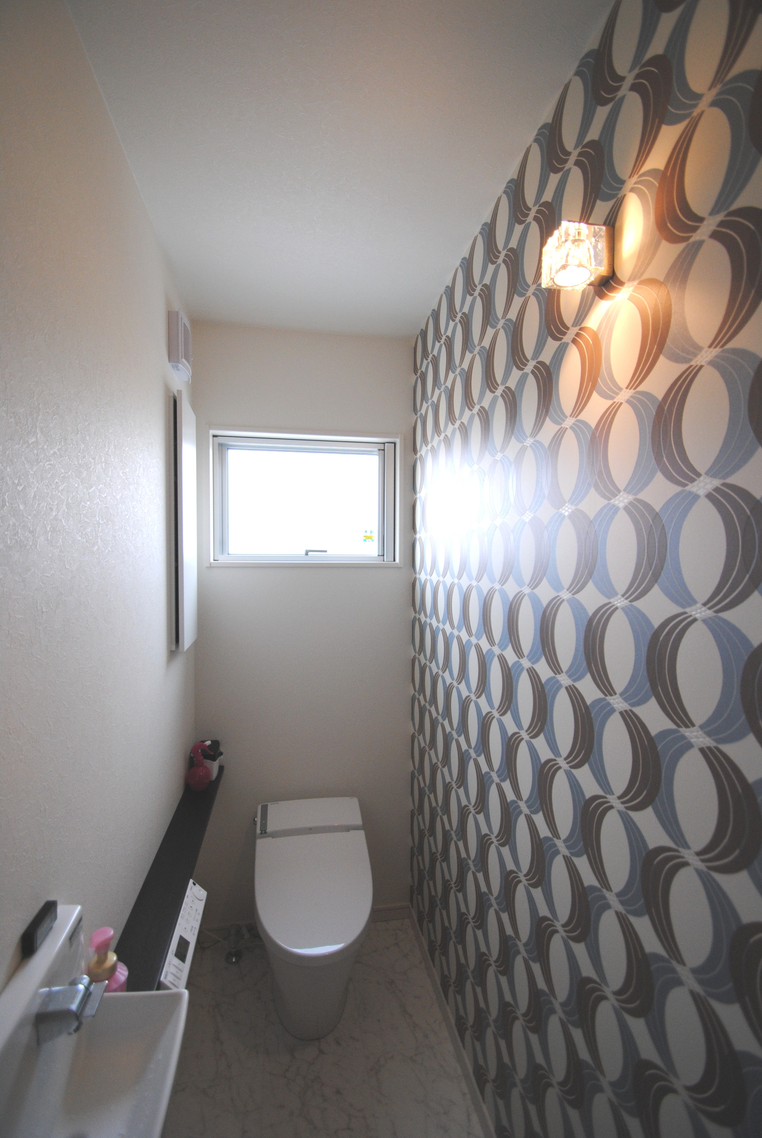 トイレにも空間の狭さを感じさせない大胆な柄を使用。壁面を照らす照明もよい雰囲気