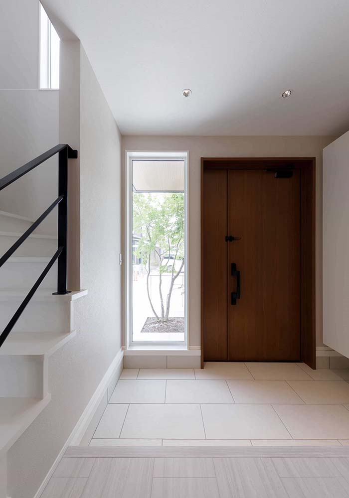 ゆったりとした玄関も大きな特徴の1つ。玄関ドア横と階段の吹き抜け部分には窓を配置することであたたかな自然光が室内に差し込む。